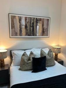a bed with two pillows and a picture on the wall at Bradford 2BR Luxury Central Apartment in Bradford