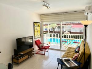 a living room with a couch and a television at Escápate al Sol Apartamento con Piscina y Playa Cercana in Playa Pobla de Farnals