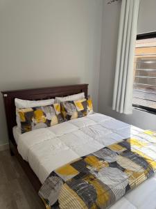 un lit avec une couette et des oreillers dans une chambre dans l'établissement MY Home Apartments, à Lusaka