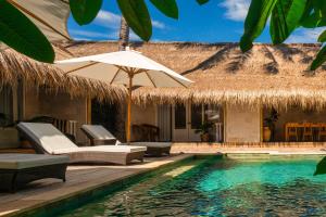 ギリ・アイルにあるSol Villas - Modern Tropical Staysのスイミングプールと茅葺き屋根のリゾート