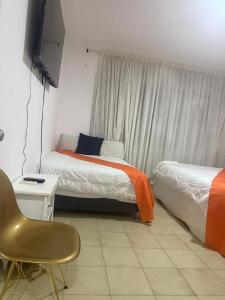 a bedroom with two beds and a chair and a television at Casa Grande in Barranquilla