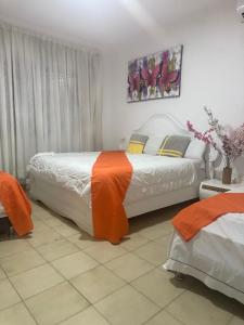 a bedroom with two beds with orange and white sheets at Casa Grande in Barranquilla