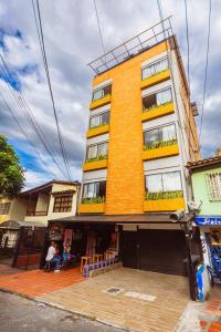 a tall yellow building with balconies on a street at Comuna Loft in Medellín