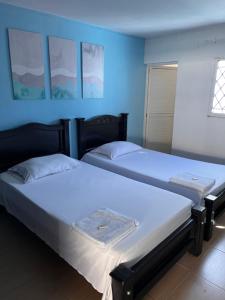 two beds in a room with blue walls at Casa Hostal Rico Vacile in Valledupar