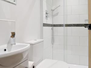 a white bathroom with a sink and a shower at Robin Cottage - Ukc3436 in Newton Abbot +5 photos