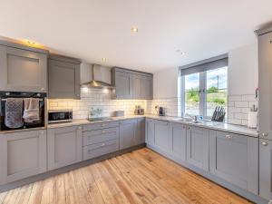 a large kitchen with gray cabinets and a large window at Ty Godro - Uk12745 in Acrefair