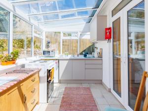 cocina con armarios blancos y techo de cristal en Littlehaven, en Ventnor
