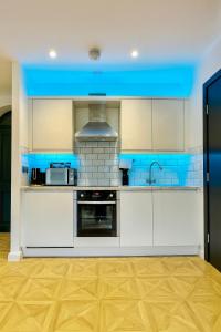 a kitchen with white cabinets and a blue ceiling at Canal Side Luxury Apartment in Leeds City Centre Sleeps 3 in Leeds
