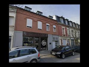 twee auto's geparkeerd voor een winkel in een straat bij SQ'Appart-y in Saint-Quentin