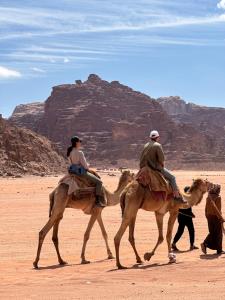 two people riding on camels in the desert at Rum Sky Experiences in Wadi Rum