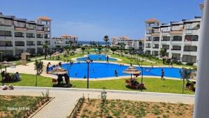 a large swimming pool in a park next to some buildings at BERALMAR RESIDENCE Privée en terrasse rez-de-jardin pied dans l'eau Chez FAOUZIA in Asilah
