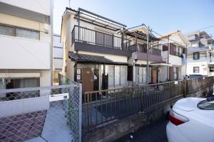 ein Mehrfamilienhaus mit einem Zaun und einem Auto in der Unterkunft Lido Urayasu in Tokio