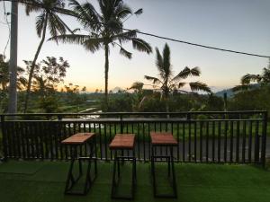 a table and two stools on a balcony with palm trees at Casa Sundara in Patjung