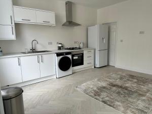 a kitchen with white cabinets and a stove and refrigerator at The Beige House in Batley +20 photos