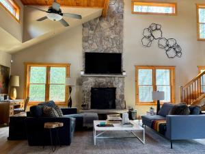 a living room with blue couches and a stone fireplace at Tuthill Tree House - Secluded Mountain Cabin with Roof Deck in Shohola +29 photos