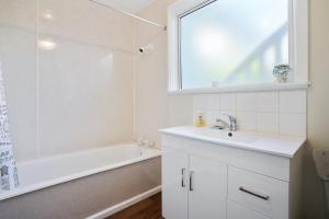 a white bathroom with a sink and a shower at Le Solterre - Akaroa Holiday Home in Akaroa +11 photos