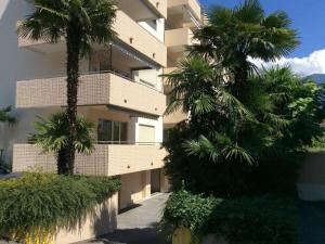 Un edificio con dos palmeras delante. en 1-bedroom apartment, en Ascona