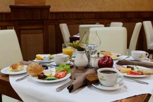 una mesa con platos de comida y tazas de café en David Boutique Hotel, en Cracovia