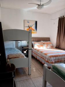 Un dormitorio con dos literas y un ventilador de techo. en Edicula com um quarto banheiro e piscina e lazer, en Foz do Iguaçu