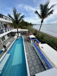 a swimming pool next to a beach with palm trees at Omawas Surf 