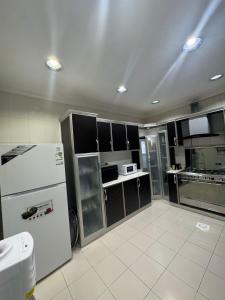a kitchen with a white refrigerator and black cabinets at فيلا فيو السلطان in Abha