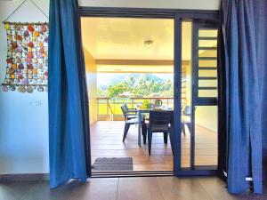a dining room with blue curtains and a table with chairs at Teahupo'o Lodge Tahiti - Maison familiale au cœur du village - Canoës inclus in Teahupoo +14 photos