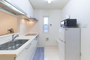 a white kitchen with a sink and a refrigerator at Soshigaya Apartment by Tranova in Kamatachō