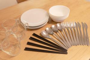 a table with plates and forks and glasses on it at Soshigaya Apartment by Tranova in Kamatachō