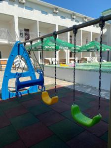 a swing set in a playground with a pool at OSTRIV Hotel in Zatoka