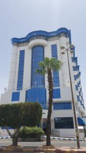 un edificio con una palmera delante de él en Qasr Al Sahab, en Khamis Mushayt