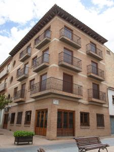 a large brick building with balconies and two benches at Hostal Aragon in Ejea de los Caballeros