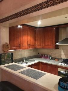 Una cocina con gabinetes de madera y un fregadero. en Plaza Luxury Apartment, en Marrakech