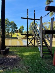 ein Holzspielplatz mit Rutsche neben einem Fluss in der Unterkunft Chácara Cidade da Divina Misericórdia in Araucária