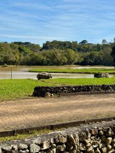 eine Steinmauer neben einem Feld mit einem Fluss in der Unterkunft Chácara Cidade da Divina Misericórdia in Araucária