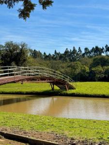 eine Brücke über einen Fluss neben einem Feld in der Unterkunft Chácara Cidade da Divina Misericórdia in Araucária