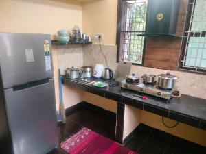 a kitchen with a refrigerator and a counter with pots and pans at Dom's Inn in Mangalore