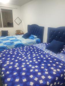 a bedroom with two beds with blue comforter at Apartamento campestre guaduales en el estadio in Santa Rosa de Cabal