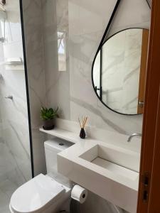 a white bathroom with a sink and a mirror at Aconchegante Apt em Lagoa Santa MG in Lagoa Santa