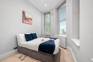 a small bedroom with a bed with blue pillows at The Kensington Residence - Central London Base in London