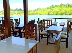 un ristorante con tavoli e sedie e vista sull'acqua di Logbond Cozy Guesthouse a Pulau Saonek-kecil