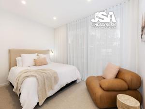 a bedroom with a bed and a chair at Willow Bay Chalet in Jindabyne