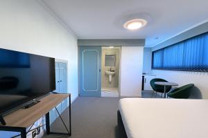 ein Schlafzimmer mit einem Bett und ein Badezimmer mit einer Toilette in der Unterkunft Pure Motel in Rotorua