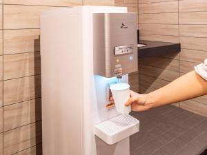 a person holding a cup in a coffee machine at APA Hotel & Resort Osaka Namba Ekimae Tower in Osaka