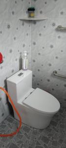 a white toilet in a bathroom with an orange hose at Noor Roomstay in Taiping