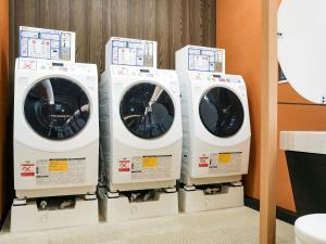 three washing machines are lined up in a room at APA Hotel & Resort Osaka Namba Ekimae Tower in Osaka