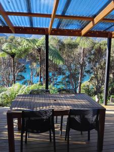 a table and chairs on a deck with a blue roof at Haven Cabin - No road access - just a boat ride away in Endeavour Inlet