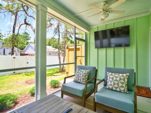 a screened in porch with two chairs and a television at The Salty Ace in Oak Island