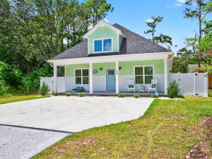 a green house with a white fence at The Salty Ace in Oak Island