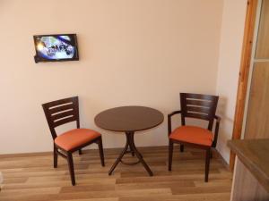ハイドゥソボスローにあるÁgnes Vendégházのテーブル、椅子2脚、壁掛けテレビ