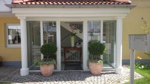 eine abgeschirmte Veranda mit zwei Topfpflanzen in der Unterkunft Ferienwohnungen Birkenhof in Bad Wörishofen